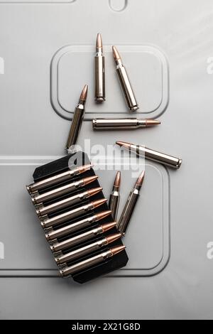 Kaliber .223 Kartuschen in silbernen Hüllen auf gebürstetem Metall. Munition für Waffen. Heller Hintergrund. Stockfoto