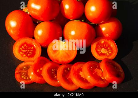 Gartentomate (Solanum lycopersicum, Lycopersicon esculentum), frische Tomaten, ganz, halbiert und in Scheiben geschnitten Stockfoto
