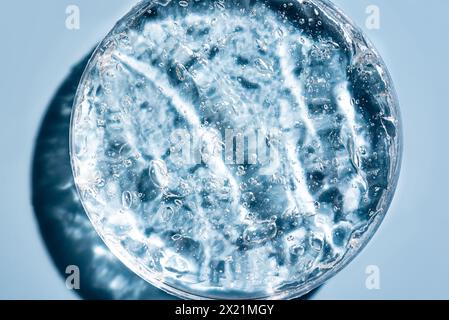 Geltextur mit Blasen in Petrischale auf blauem Hintergrund. Kosmetische Laborforschung und Kollagenbestandteil für die Hautpflege. Stockfoto