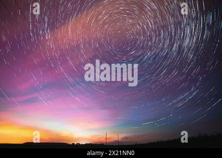 Heller Nächtlicher Sternenhimmel. Sanfte Blau-Orange-Rosa-Farben. Erstaunliche Sternenpfade Im Hintergrund Des Nachthimmels. Sternenspuren Über Der Stromleitung. Große Belichtung Stockfoto