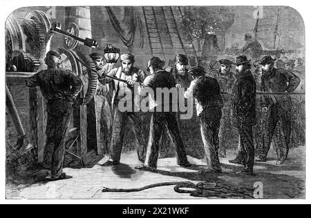 Wir untersuchen das Atlantic Telegraph Cable, nachdem wir es an Bord der Great Eastern 1865 hochgehoben haben. Gravur einer Skizze von Robert Dudley von der besorgten Gruppe von Männern, die das Kabel handhaben und inspizieren... ein Fehler in der elektrischen Isolierung des Kabels...[wurde] festgestellt, und eine Länge von zehn Meilen, die im Gefolge des Schiffes untergetaucht war, wurde wieder aufgefangen, um zu untersuchen, wo die Störung lag; daraufhin wurde festgestellt, dass ein winziges Stück losen Eisendraht durch die äußere Abdeckung und die Guttapercha um den elektrischen Draht gedrungen war, um mit dem letzteren in Berührung zu kommen; und Stockfoto