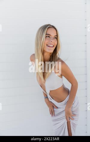 Eine junge, schöne blonde Frau posiert anmutig in einem fließenden weißen Kleid am Miami Beach. Stockfoto