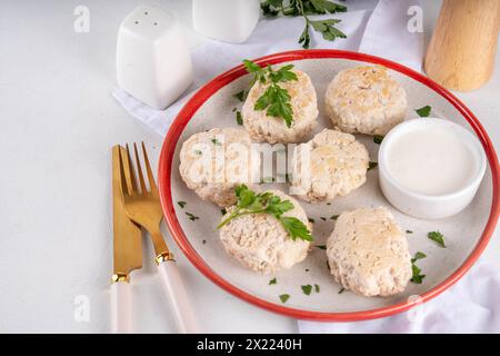 Gedämpfte Hühnchenkoteletts, Fleischbällchen mit Kräutern und weiße Soße auf dem Küchentisch Hintergrund. Diät weißes Geflügel gemahlenes Fleisch Lebensmittel Rezept Stockfoto