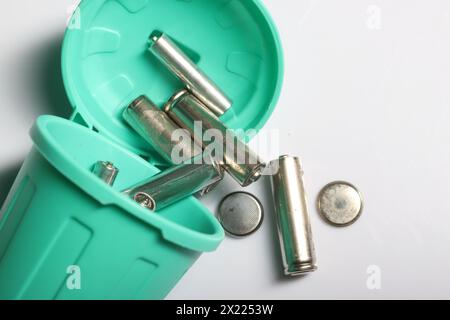 Miniaturszene mit einer starken Botschaft: Alte Fingerbatterien in einem winzigen Abfalleimer, die sich für Recycling und Umweltbewusstsein einsetzen Stockfoto