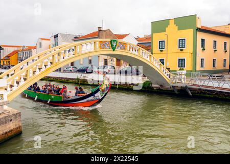 Touristen auf einem Boot, das durch den Central Canal segelt. Farbenfrohe Häuser am Canal Central. Malerische und wunderschöne Kleinstadt Aveiro in Portugal. Ein berühmter Stockfoto