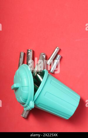 Gebrauchte Fingerbatterien in einem Miniatur-Mülleimer. Rosafarbener Hintergrund. Nahaufnahme. Feld für Text. Stockfoto