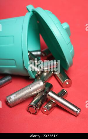 Gebrauchte Fingerbatterien in einem Miniatur-Mülleimer. Rosafarbener Hintergrund. Nahaufnahme. Stockfoto