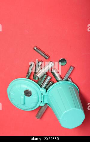 Gebrauchte Fingerbatterien in einem Miniatur-Mülleimer. Rosafarbener Hintergrund. Stockfoto