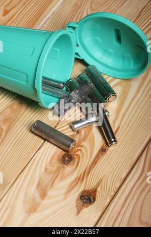 Gebrauchte Fingerbatterien in einem Miniatur-Mülleimer. Kiefernbretter. Stockfoto