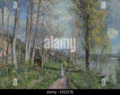 Ufer der seine bei By, 1880-81. Ein junges Mädchen in einem blauen Kleid, vermutlich Sisley&#x2019;s Tochter Jeanne, geht auf einem Weg an der seine entlang. Es handelt sich um eine Gruppe von Gemälden lokaler Flüsse, die der Künstler kurz nachdem er und seine Familie in der Nähe von Moret-sur-Loing südöstlich von Paris niedergelassen hatten. Eine Streuung weißer und gelber Blumen deutet darauf hin, dass die Szene im Frühjahr gemalt wurde. Stockfoto