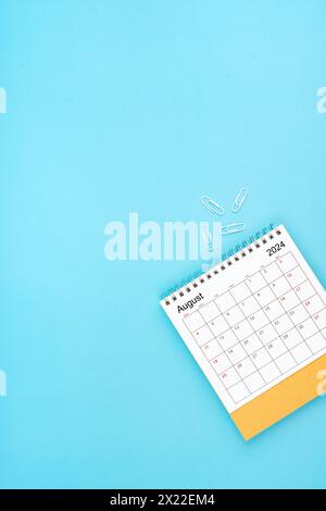 Schreibtischkalender für August 2024 und weiße Büroklammer auf hellblauem Hintergrund Stockfoto