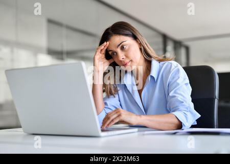 Besorgte, ermüdete Geschäftsfrau mittleren Alters, die Kopfschmerzen bei der Arbeit hat. Stockfoto