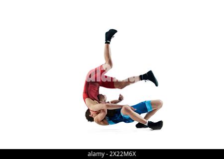 Junge Männer, Athleten, die sich in einem anspruchsvollen Wrestling-Match engagieren, demonstrieren Widerstandsfähigkeit und Fähigkeiten isoliert auf weißem Hintergrund Stockfoto