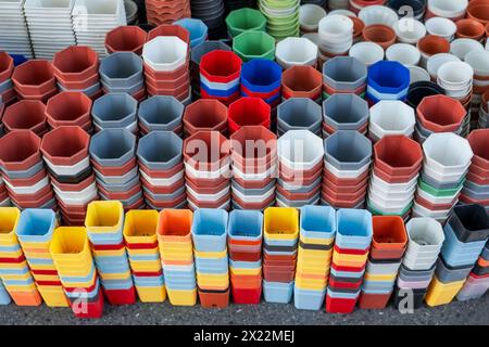 Viele verschiedene Formen, runde, quadratische und farbige Plastiktöpfe für den Anbau von Pflanzen auf der Theke in einem Gartengeschäft. Stockfoto