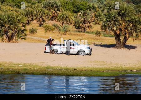 Vier ägyptische Männer mit einem in Toyota Hilux festgefahrenen Pickup-Truck am Ufer des Nils in Assuan, Ägypten. Stockfoto