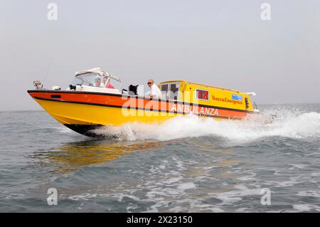 AMBULANZA, Ein gelbes Rettungsboot, das über das Meer läuft, während es Wellen macht, Venedig, Venetien, Italien Stockfoto