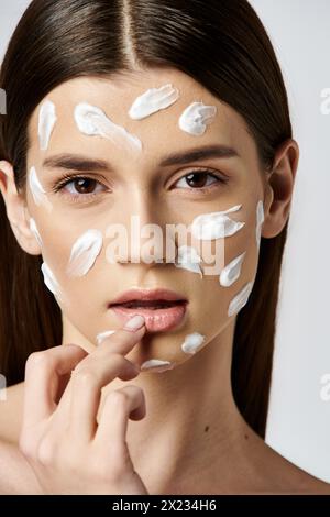 Eine auffällige junge Frau in einer weißen Creme, die einen Hauch von Geheimnis und Eleganz ausstrahlt. Stockfoto