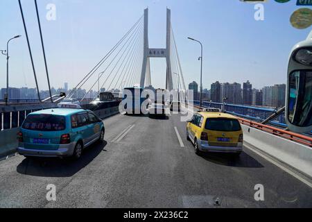 Verkehr in Shanghai, Shanghai Shi, Volksrepublik China, Verkehr auf einer Stadtbrücke mit Wolkenkratzern im Hintergrund und hellem Sonnenlicht Stockfoto