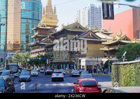 Verkehr in Shanghai, Shanghai Shi, Volksrepublik China, traditioneller Tempel vor modernen Gebäuden auf einer städtischen Straße mit Verkehr Stockfoto