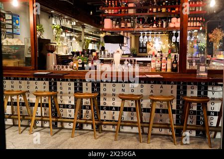 Abendlicher Spaziergang durch Shanghai zu den Sehenswürdigkeiten, Shanghai, leere Bar mit Stühlen und verschiedenen Flaschen, im Hintergrund eine Wand mit Typografie Stockfoto