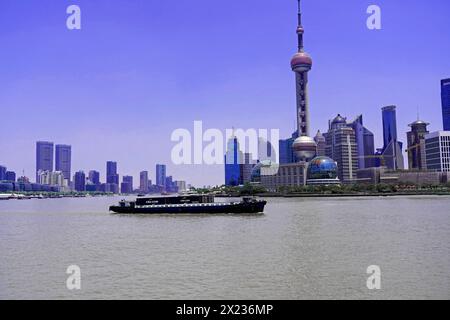 Machen Sie einen Spaziergang durch Shanghai zu den Sehenswürdigkeiten Shanghai, China, Asien, Ein Frachtschiff segelt auf dem Fluss vor der Skyline von Shanghai Stockfoto