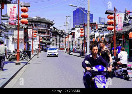 Machen Sie einen Spaziergang durch Shanghai zu den Sehenswürdigkeiten, Shanghai, China, Asien, belebte Stadtstraße mit traditioneller chinesischer Architektur und einem Roller Stockfoto