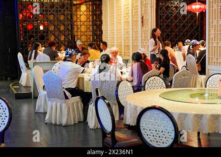 Abendessen in einem eleganten Restaurant in Shanghai, China, Asien. Gäste genießen eine Mahlzeit auf einer von Eleganz und sanfter Beleuchtung umgebenen Restaurantterrasse, Shanghai Stockfoto