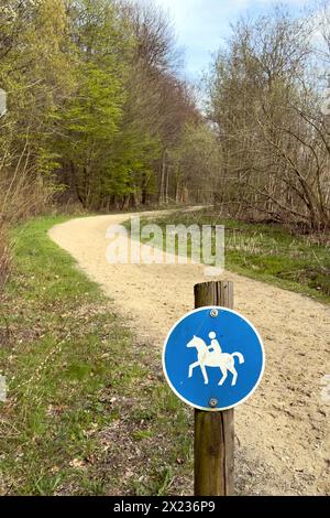 Schild für Fahrer vor dem ausgeschilderten Reitweg mit weichem Sandboden, der im Frühjahr durch Mischwald führt Stockfoto