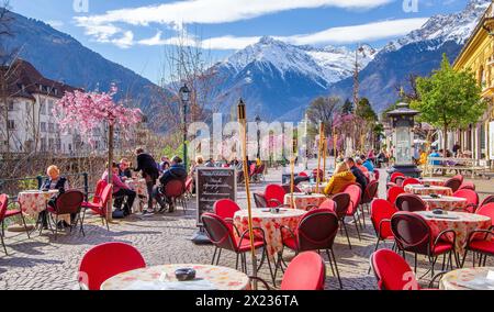 Winterpromenade entlang der Passer mit Straßencafé im Hintergrund Texelgruppe mit dem Gipfel 3006 m im Frühjahr, Meran, Passtal, Etsch Stockfoto