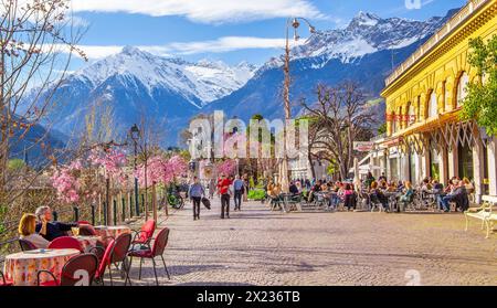 Winterpromenade entlang der Passer mit Straßencafé im Hintergrund Texelgruppe mit dem Gipfel 3006 m im Frühjahr, Meran, Passtal, Etsch Stockfoto