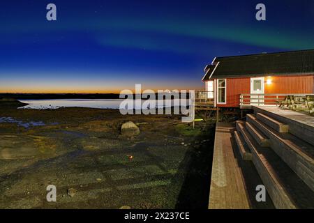 Rotes Gebäude mit Balkon am Wasser, Nordlichter (aurora borealis), Rorbuer, Urlaub, Unterkunft, Lovund, Lovunden, Helgeland-Küste, Norwegen Stockfoto