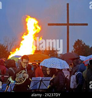 Musiker mit Doppelhorn vor dem Osterfeuer an der Haniel-Verderbungspitze mit dem Gipfelkreuz im Regen, Bottrop, Ruhrgebiet, Deutschland Stockfoto