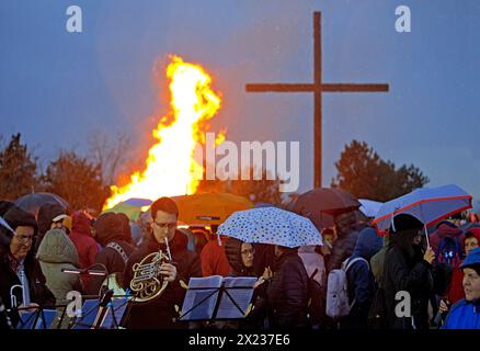 Musiker mit Doppelhorn vor dem Osterfeuer an der Haniel-Verderbungspitze mit dem Gipfelkreuz im Regen, Bottrop, Ruhrgebiet, Deutschland Stockfoto