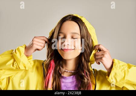 Ein stilvolles Teenager-Mädchen in einem leuchtend gelben Regenmantel posiert energisch. Stockfoto