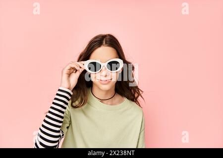 Ein modisches Teenager-Mädchen posiert energisch in einem grünen Hemd und einer stylischen Sonnenbrille und strahlt Selbstvertrauen und Stil aus. Stockfoto