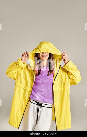 Ein stilvolles Teenager-Mädchen posiert energisch in einer gelben Jacke und einer weißen Hose und strahlt Selbstvertrauen und Eleganz aus. Stockfoto