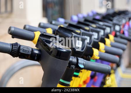 Elektroroller in einer Reihe auf dem Parkplatz. Mietsystem in der Größe, öffentliche E-Scooter auf der Straße Stockfoto