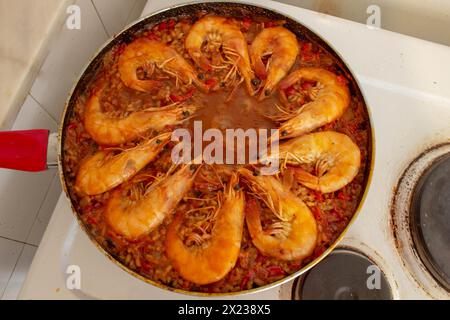 Erleben Sie kulinarische Harmonie, während die goldfrittierten Garnelen sich dem lebhaften Gemisch der Aromen in der traditionellen spanischen Paella anschließen und jeden Bissen mit s bereichern Stockfoto