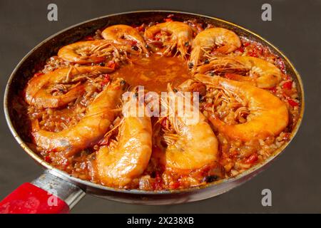 Erleben Sie kulinarische Harmonie, während die goldfrittierten Garnelen sich dem lebhaften Gemisch der Aromen in der traditionellen spanischen Paella anschließen und jeden Bissen mit s bereichern Stockfoto