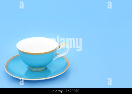 Blaue und goldene Teetasse aus Bone china. Elegantes luxuriöses Trinkset auf pastellblauem Hintergrund mit Kopierraum. Minimale Zen-Zusammensetzung. Stockfoto