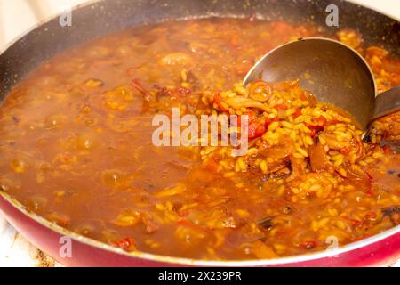 Tauchen Sie ein in die Kunst der spanischen Küche, während die lebendigen Farben und die verführerischen Aromen der Paella während der Zubereitung zum Leben erweckt werden Stockfoto