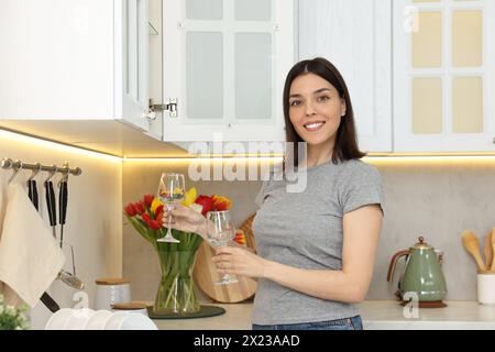 Schöne junge Frau, die zwei saubere Gläser in der Küche hält Stockfoto
