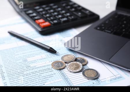 Steuerformulare, Münzen, Stift, Taschenrechner und Laptop auf dem Tisch, Nahaufnahme Stockfoto