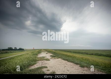 Deich- und Salzwiesen am Pilsumer Leuchtturm unter Sturmwolken, Krummhörn, Ostfriesland, Niedersachsen, Deutschland, Europa Stockfoto