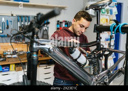 Der Fahrradmechaniker manipuliert das Aufhängungssystem eines E-Mountainbikes mit einem Ratschenschlüssel. Stockfoto