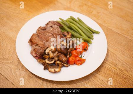 Ein gekochtes Rib Eye Steak mit Pilzen, Tomaten und grünen Bohnen Stockfoto