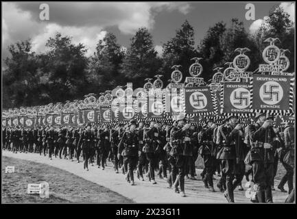 1930er Jahre Nürnberger Rallye Nazi-Deutschland. Uniformierte Soldaten in Helmen und Jackstiefeln tragen Banner mit NSDAP-Hakenkreuzen mit der Botschaft „DEUTSCHLAND ERWACHE“ Deutschland ERWACHT. Nürnberg Nürnberg Nazideutschland Stockfoto