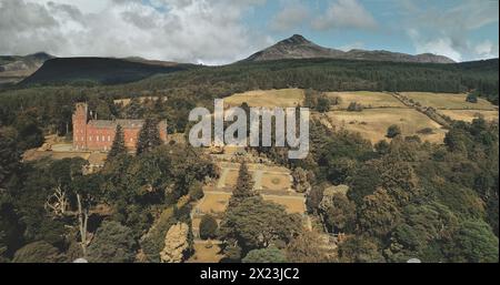 Schottlands Meereslandschaft Küstenaufnahme: Bäume und Straße mit Autos in der Nähe des Firth-of-Clyde Gulf. Herrliche Küste der Natur mit historischem Erbe: Brodick Castle und Weitblick Stockfoto