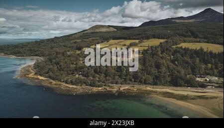 Schottland Arran Island Landschaft aus der Luft: Wälder, Wiesen, Berge am Sommertag. Wolken auf der Skyline nahe dem Goat Fell Peak. Epische Szene der Atlantikküste. Kinoaufnahme Stockfoto