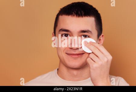 Ein Nahporträt eines Teenagers reinigt die Haut des Gesichts mit einem Schwamm. Der Junge kümmert sich um Teenager-Haut. Ein kosmetisches Verfahren. Mann Schönheit Ro Stockfoto